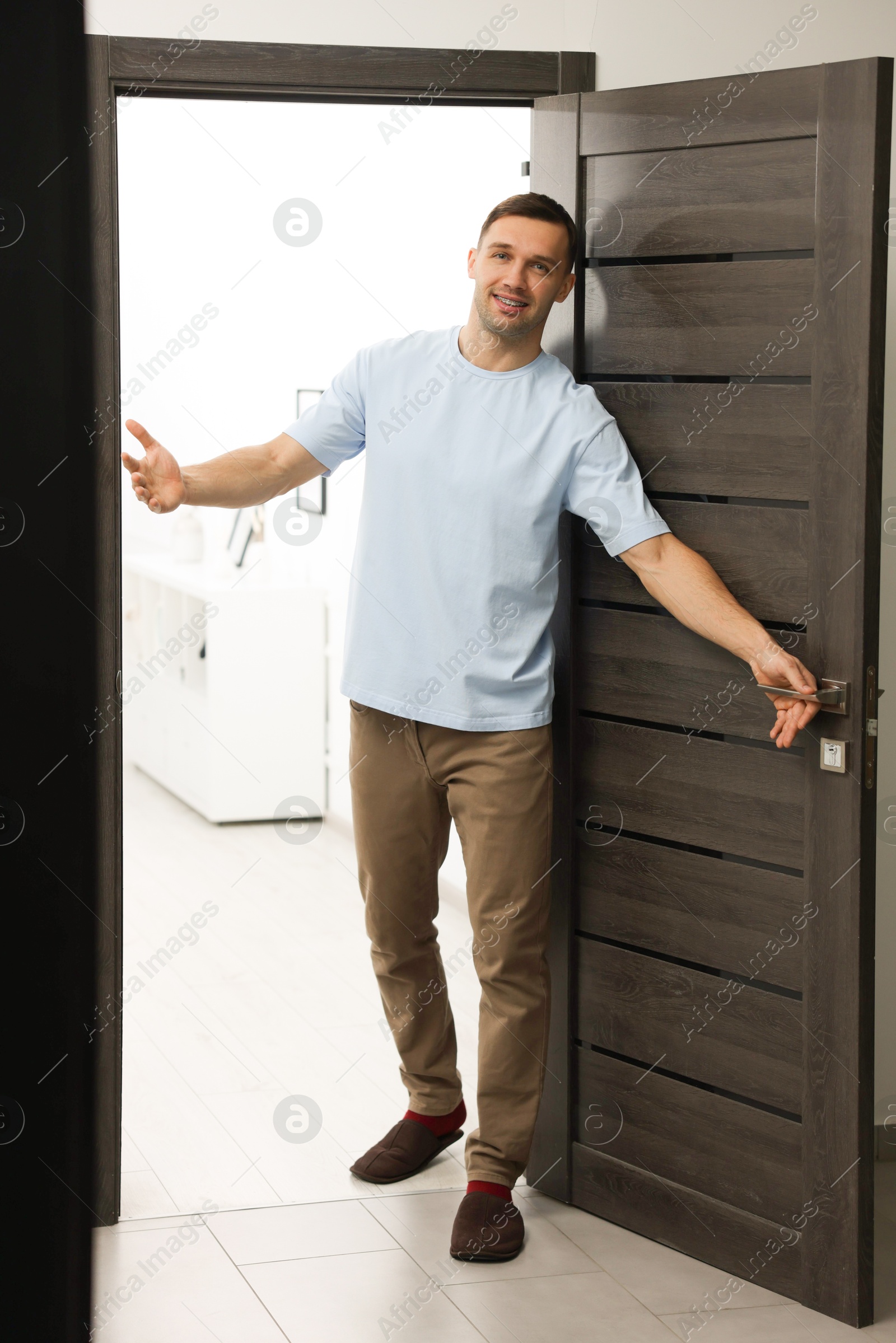 Photo of Cheerful man welcoming guests to his apartment