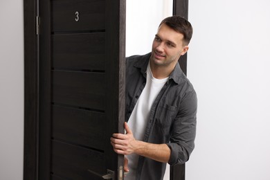 Photo of Cheerful man meeting guests in doorway of his apartment