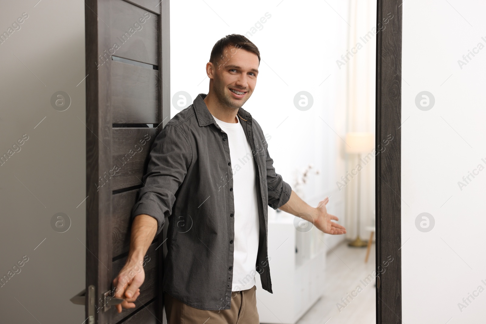 Photo of Cheerful man welcoming guests to his apartment