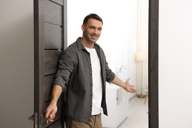 Photo of Cheerful man welcoming guests to his apartment