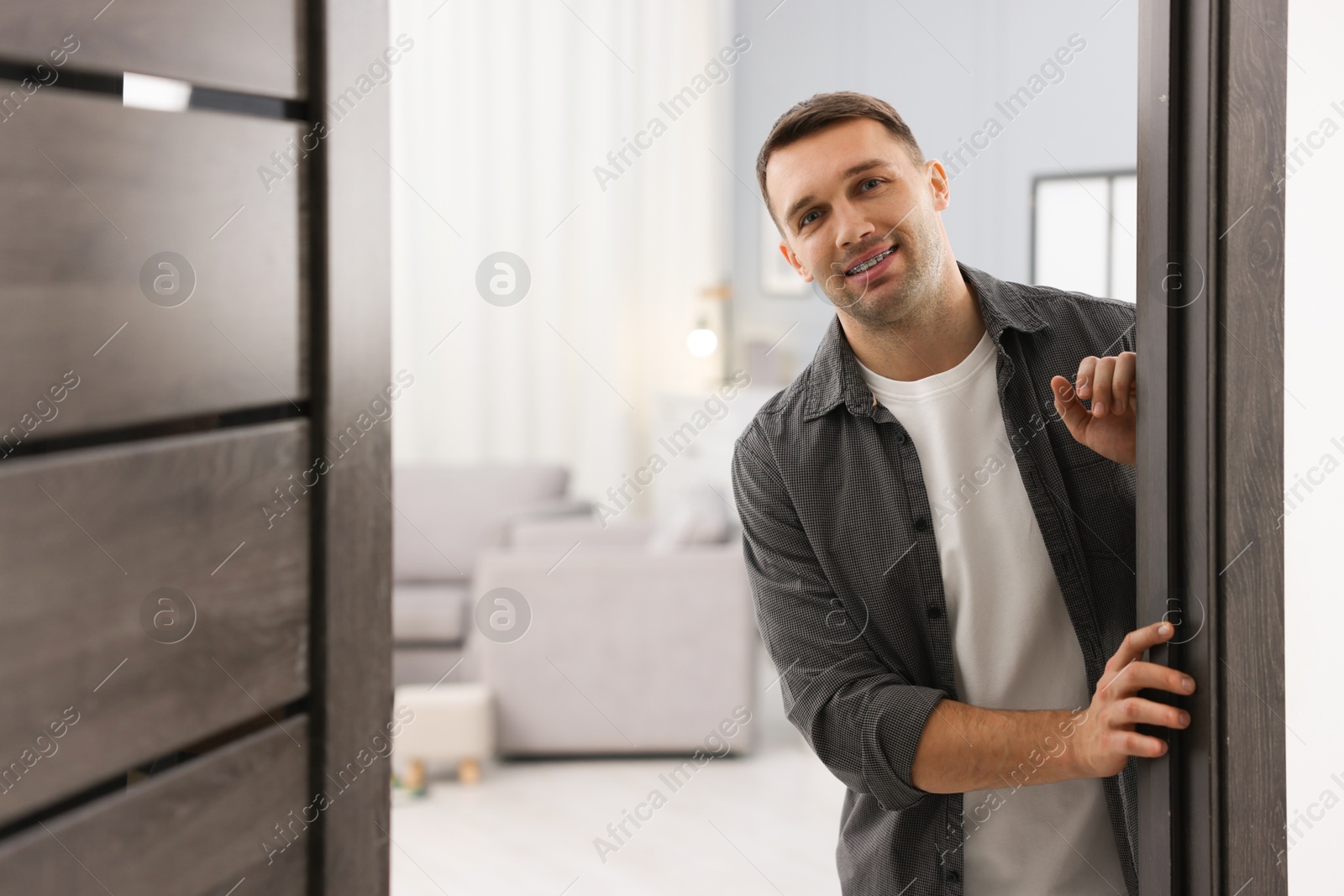 Photo of Cheerful man welcoming guests to his apartment. Space for text