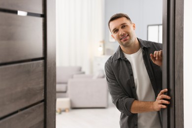 Photo of Cheerful man welcoming guests to his apartment. Space for text