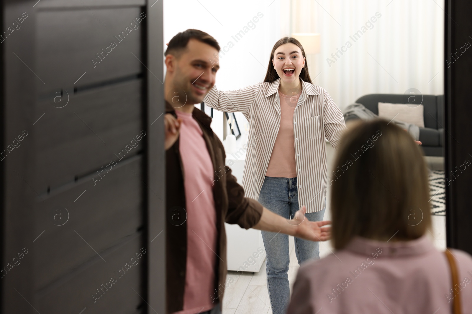 Photo of Lovely couple welcoming friend to their apartment