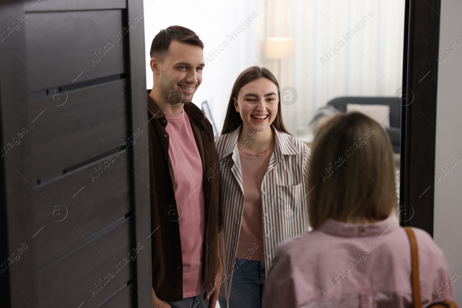 Photo of Lovely couple welcoming friend to their apartment