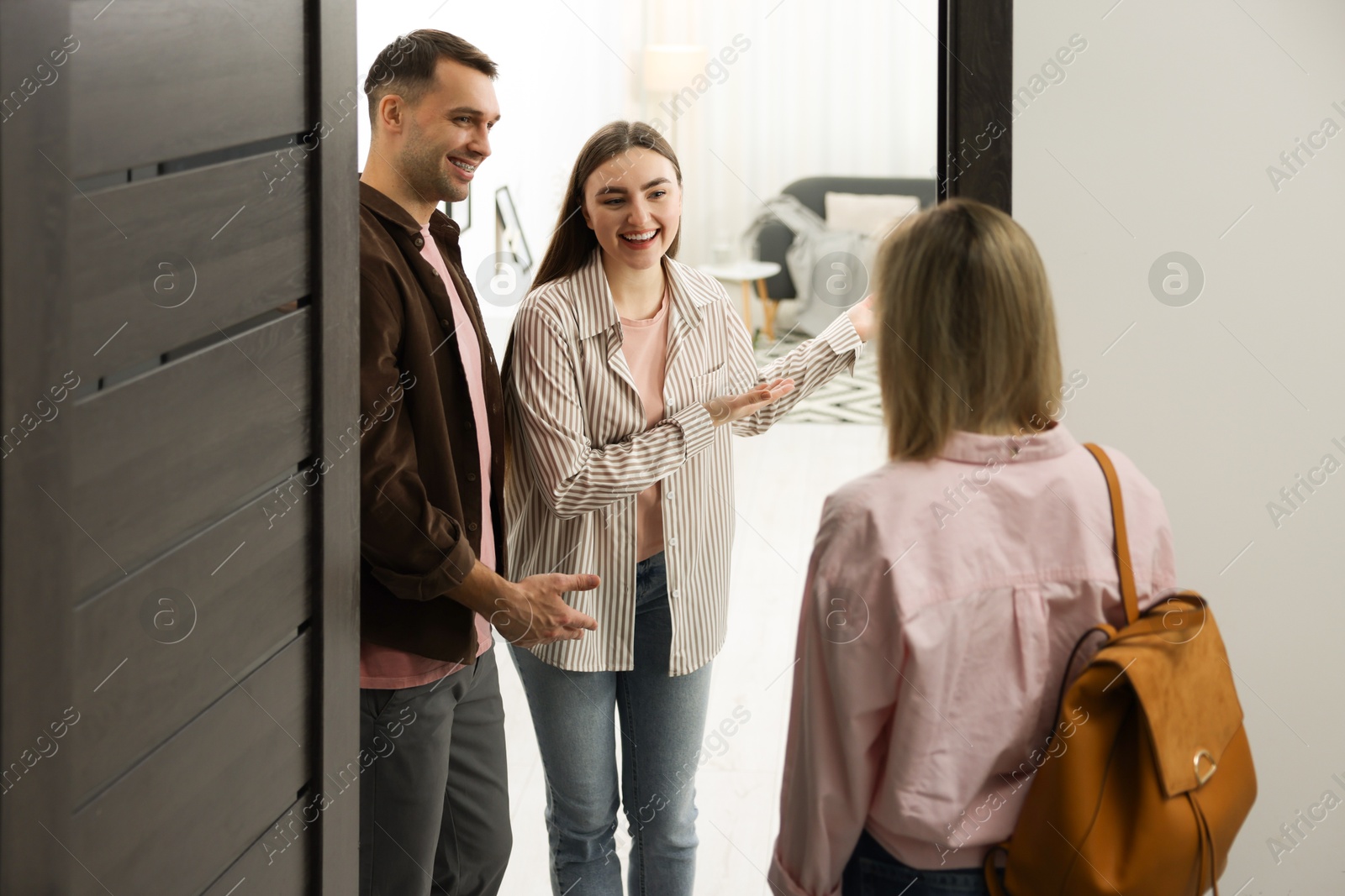 Photo of Lovely couple welcoming friend to their apartment