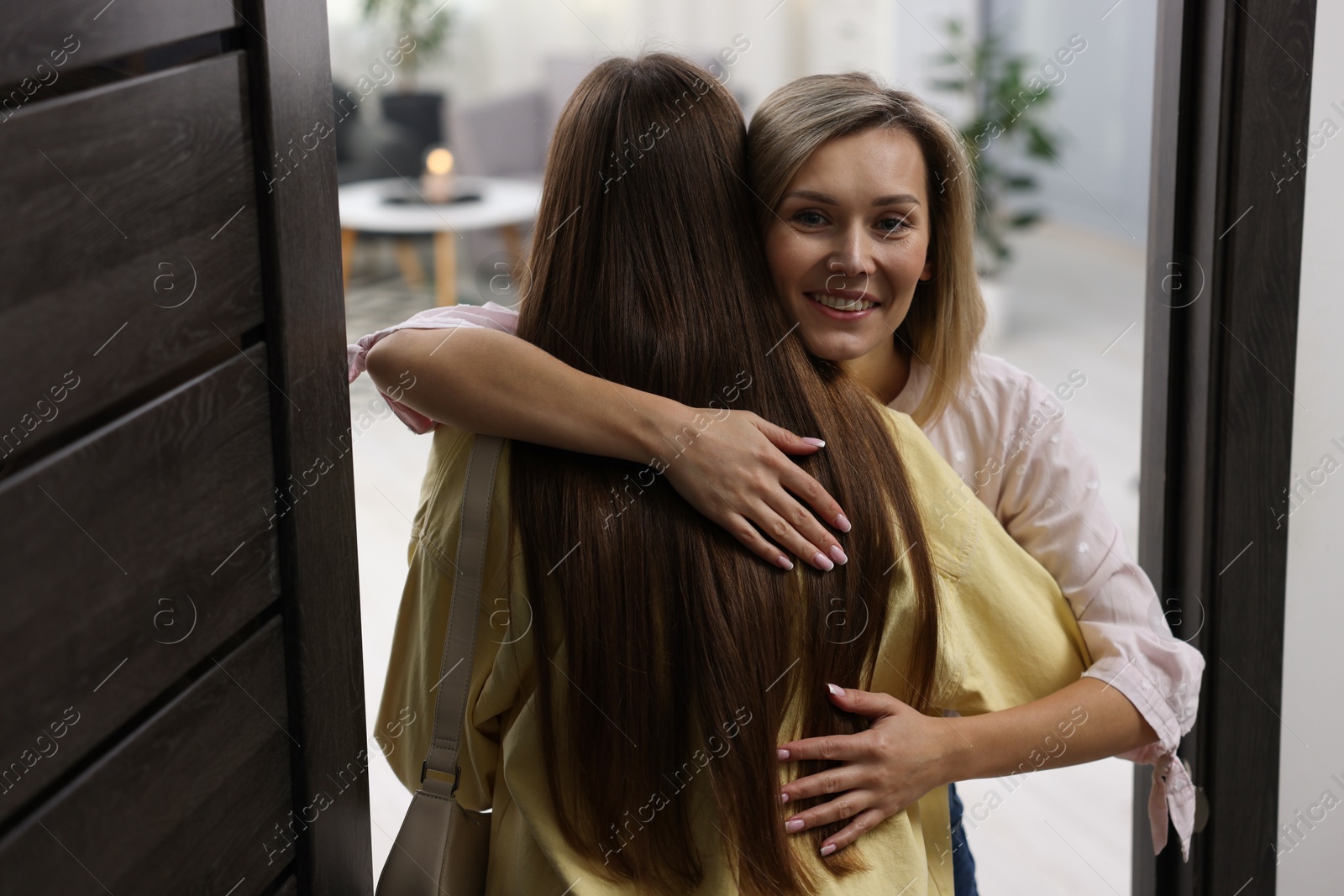 Photo of Happy woman welcoming friend to her apartment