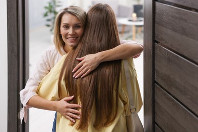 Photo of Happy woman welcoming friend to her apartment