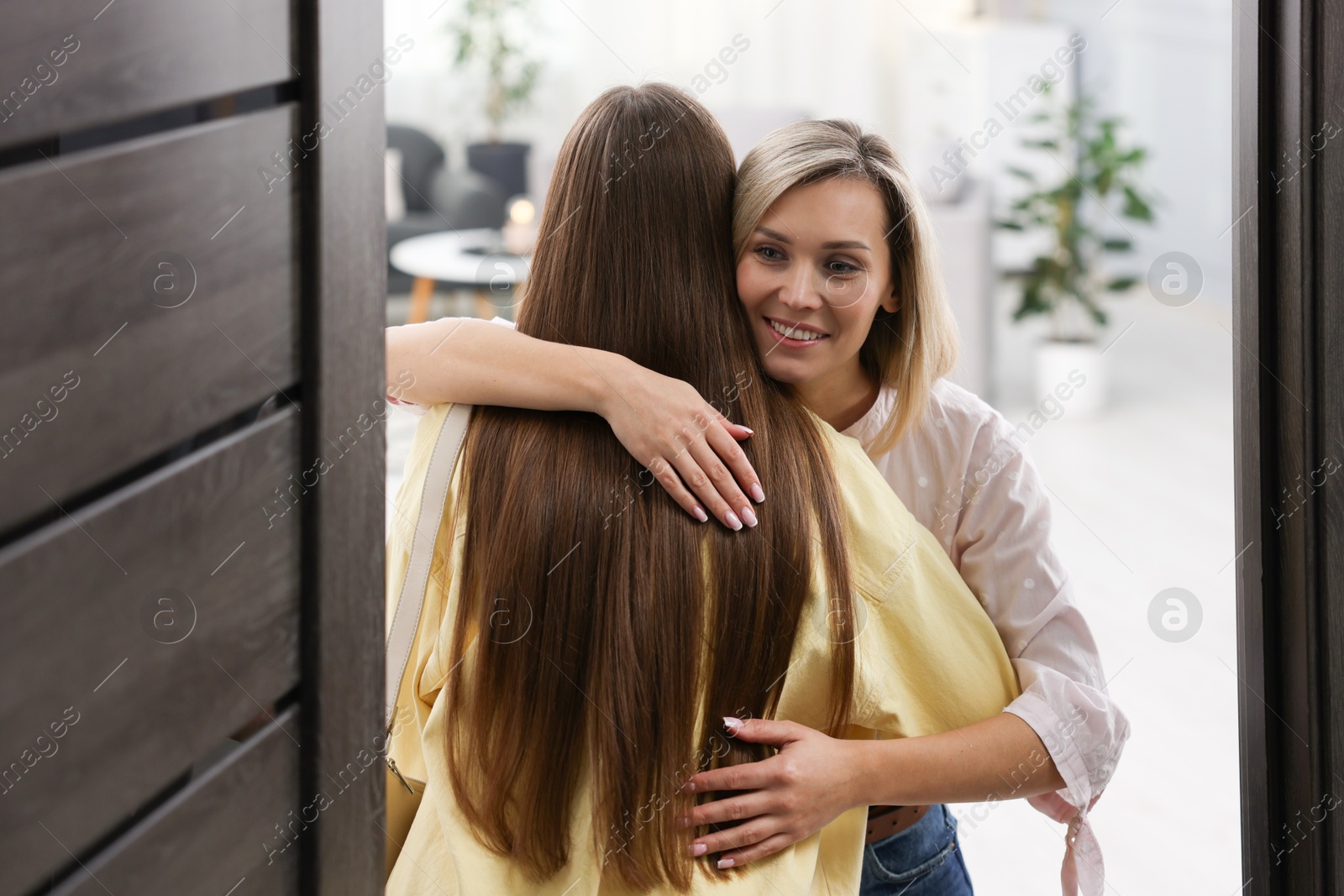 Photo of Happy woman welcoming friend to her apartment