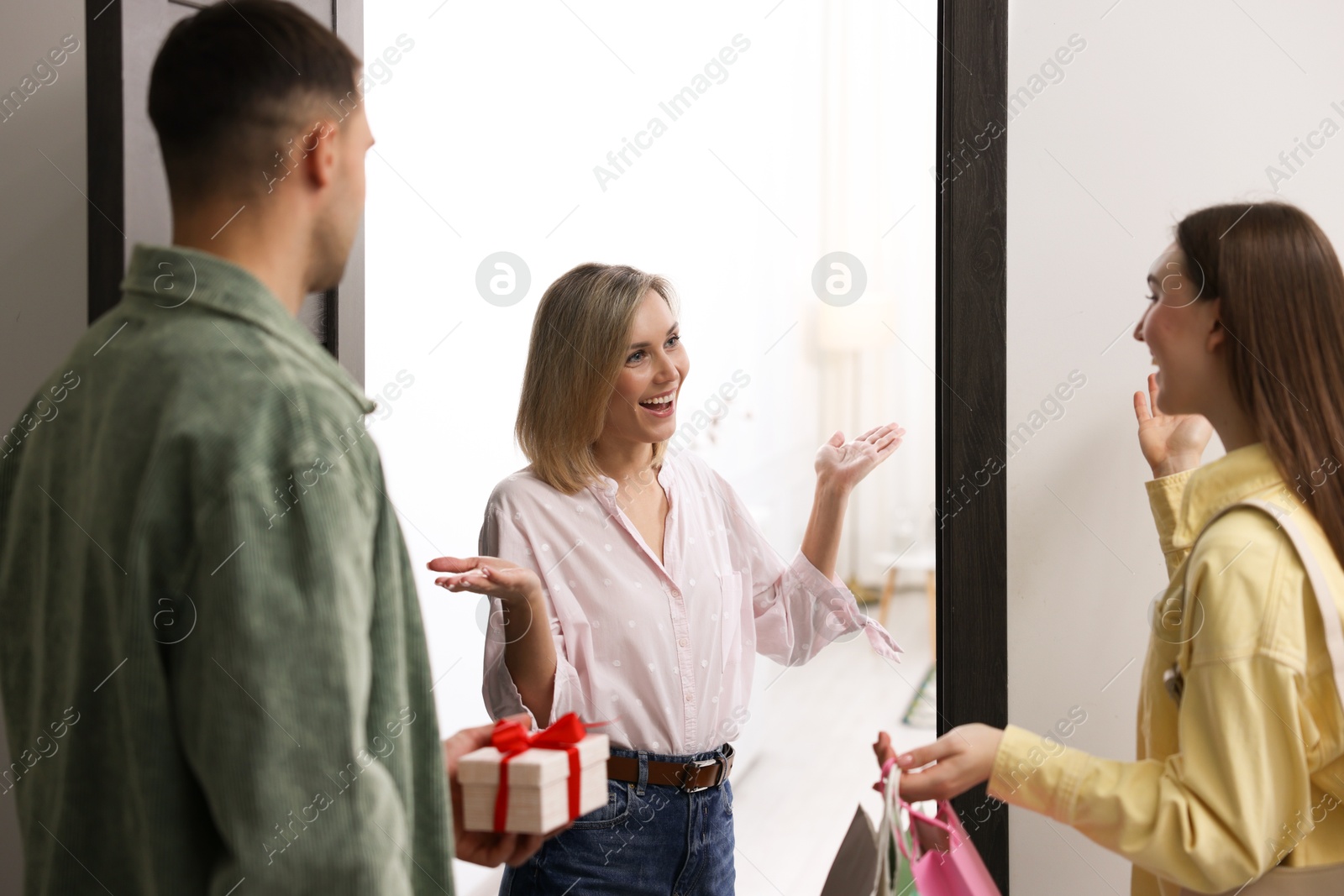 Photo of Cheerful woman welcoming guests to her housewarming party