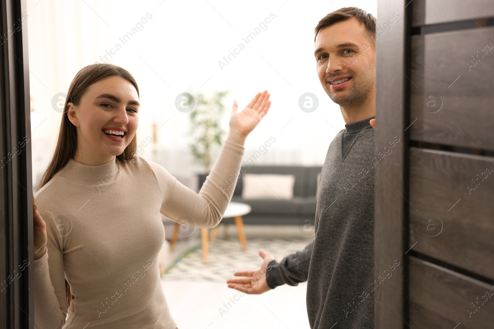 Photo of Happy couple welcoming guests to their apartment