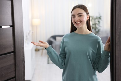 Photo of Cheerful woman welcoming guests to her apartment