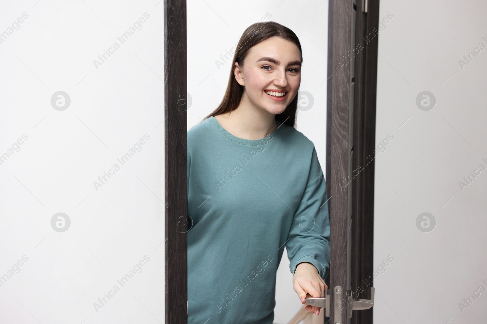 Photo of Cheerful woman welcoming guests to her apartment