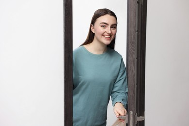 Photo of Cheerful woman welcoming guests to her apartment