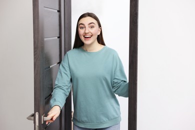 Photo of Excited woman welcoming guests to her apartment