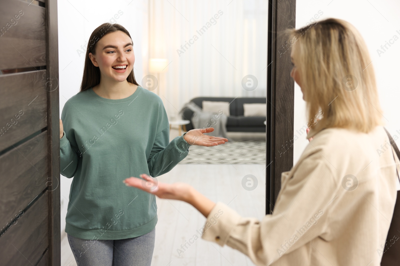 Photo of Happy woman welcoming guest to her apartment