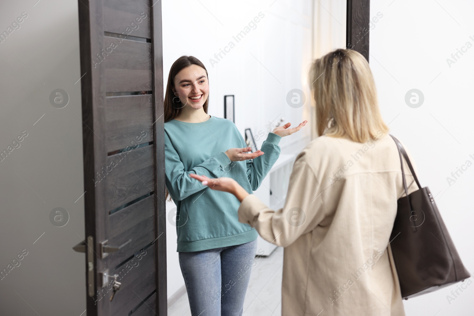 Photo of Happy woman welcoming guest to her apartment