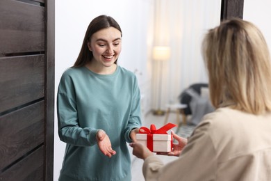 Photo of Woman giving housewarming gift to her friend at new apartment