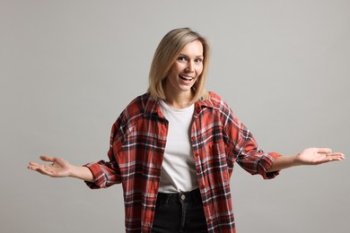 Photo of Woman welcoming friends or guests on grey background