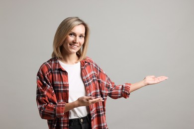 Photo of Woman welcoming friends or guests on grey background