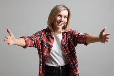 Photo of Woman welcoming friends or guests on grey background