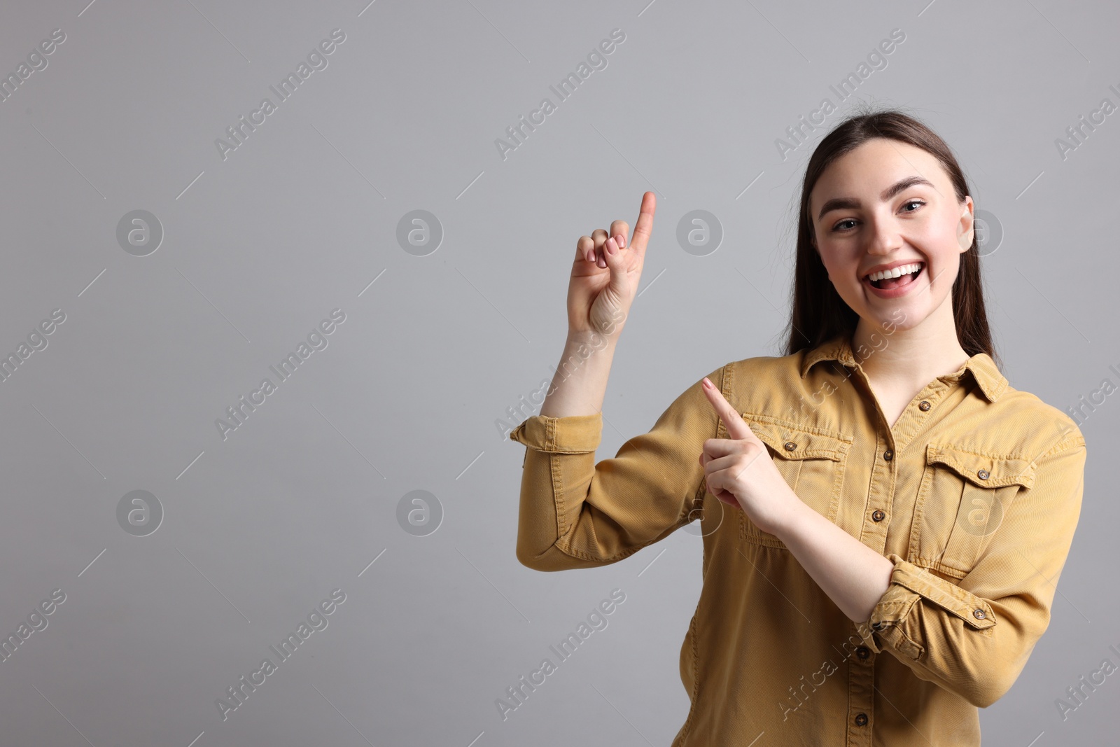 Photo of Woman welcoming friends or guests on grey background. Space for text