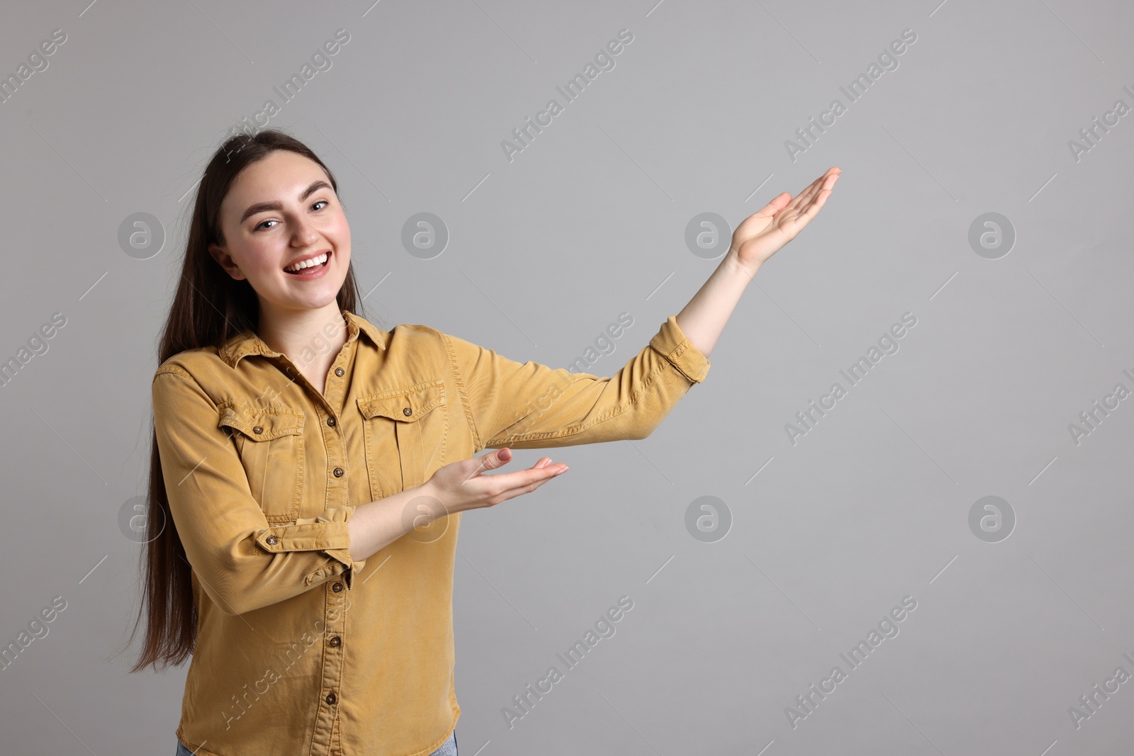 Photo of Woman welcoming friends or guests on grey background