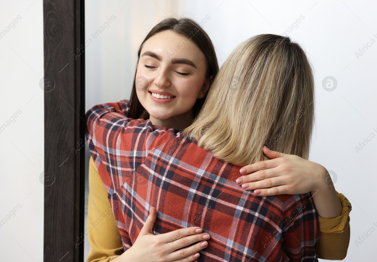 Photo of Happy woman welcoming friend to her apartment