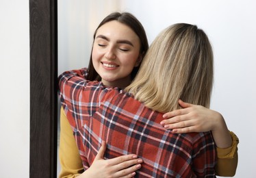 Happy woman welcoming friend to her apartment