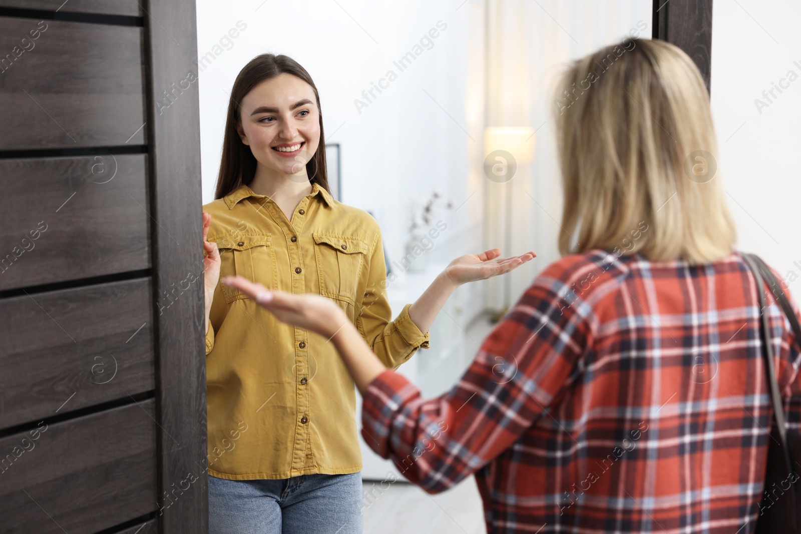 Photo of Happy woman welcoming friend to her apartment