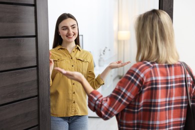 Photo of Happy woman welcoming friend to her apartment