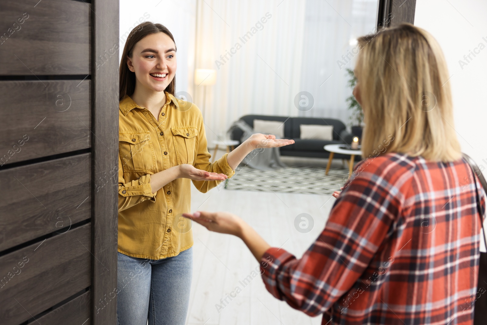 Photo of Happy woman welcoming friend to her apartment