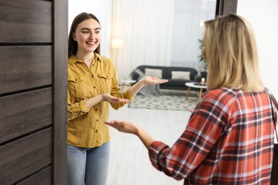 Photo of Happy woman welcoming friend to her apartment