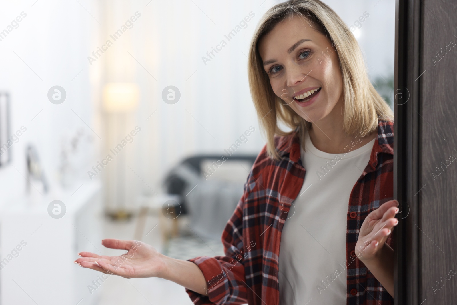 Photo of Happy woman welcoming friend to her house. Space for text