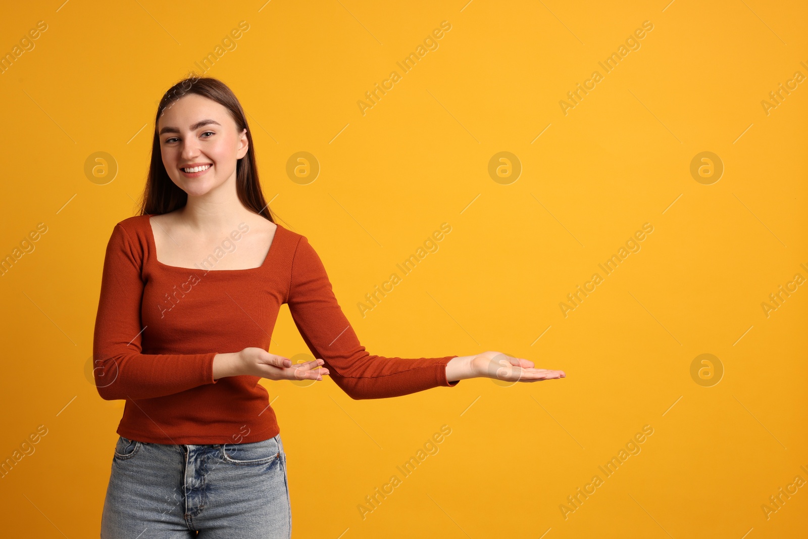 Photo of Happy woman welcoming guests on orange background. Space for text