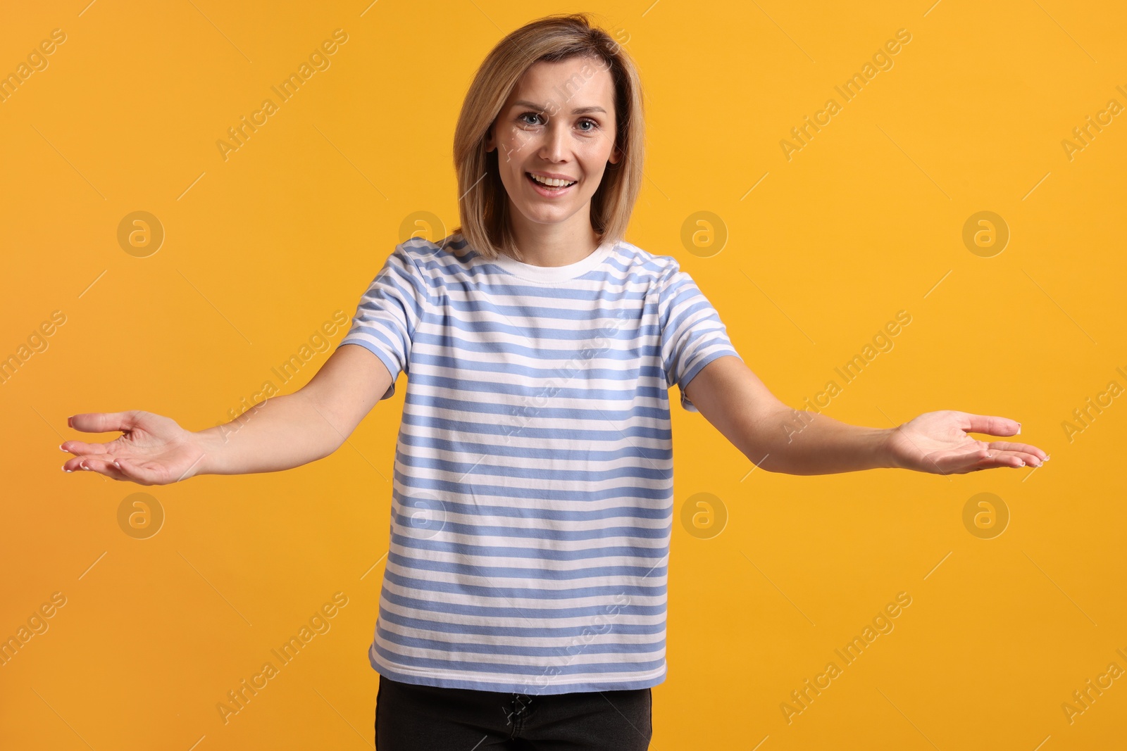 Photo of Happy woman welcoming guests on orange background