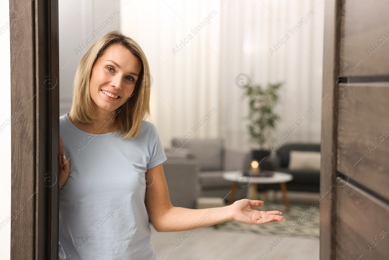 Photo of Happy woman welcoming guests to her house