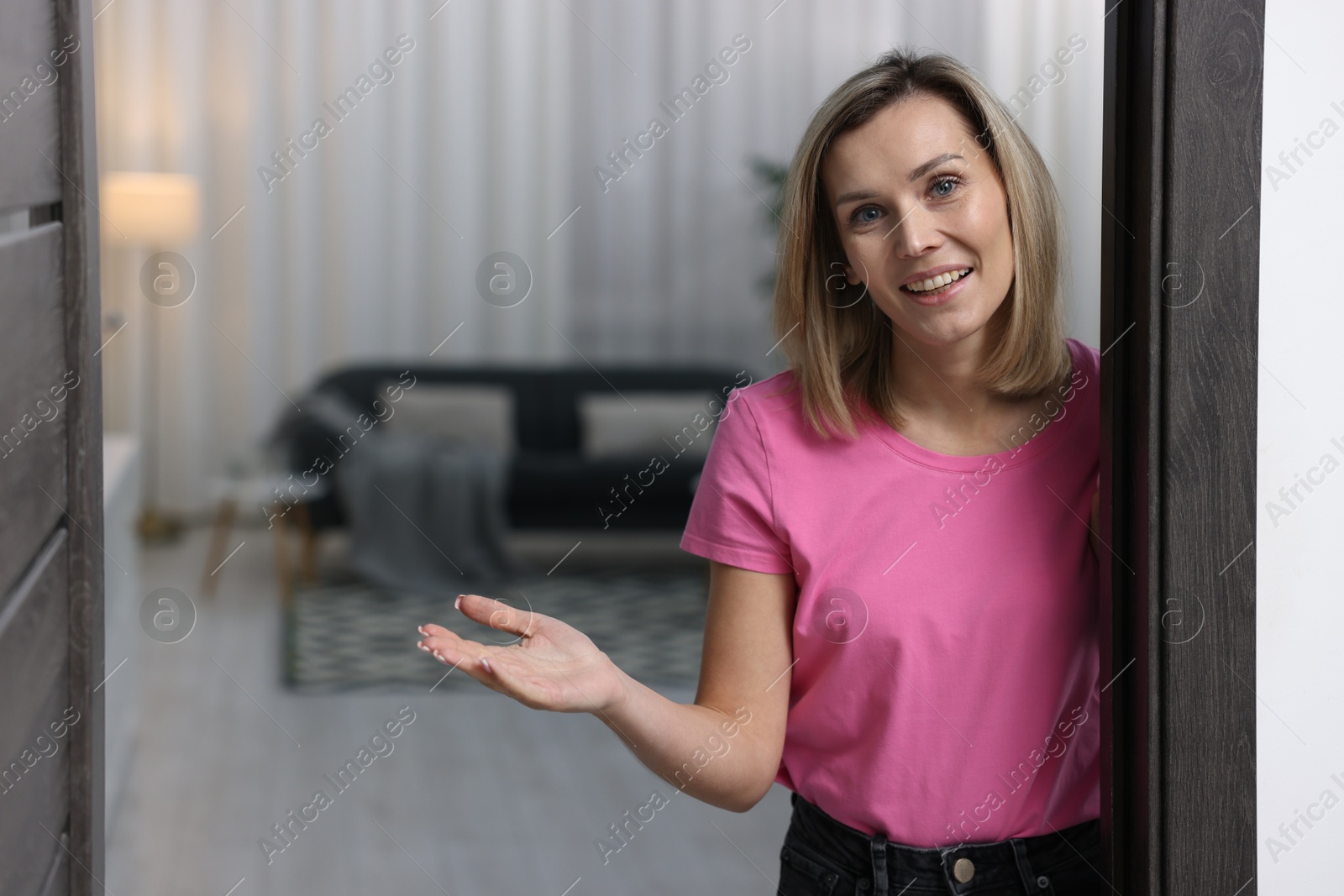 Photo of Happy woman welcoming guests to her house