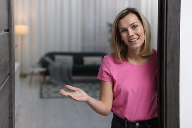 Photo of Happy woman welcoming guests to her house