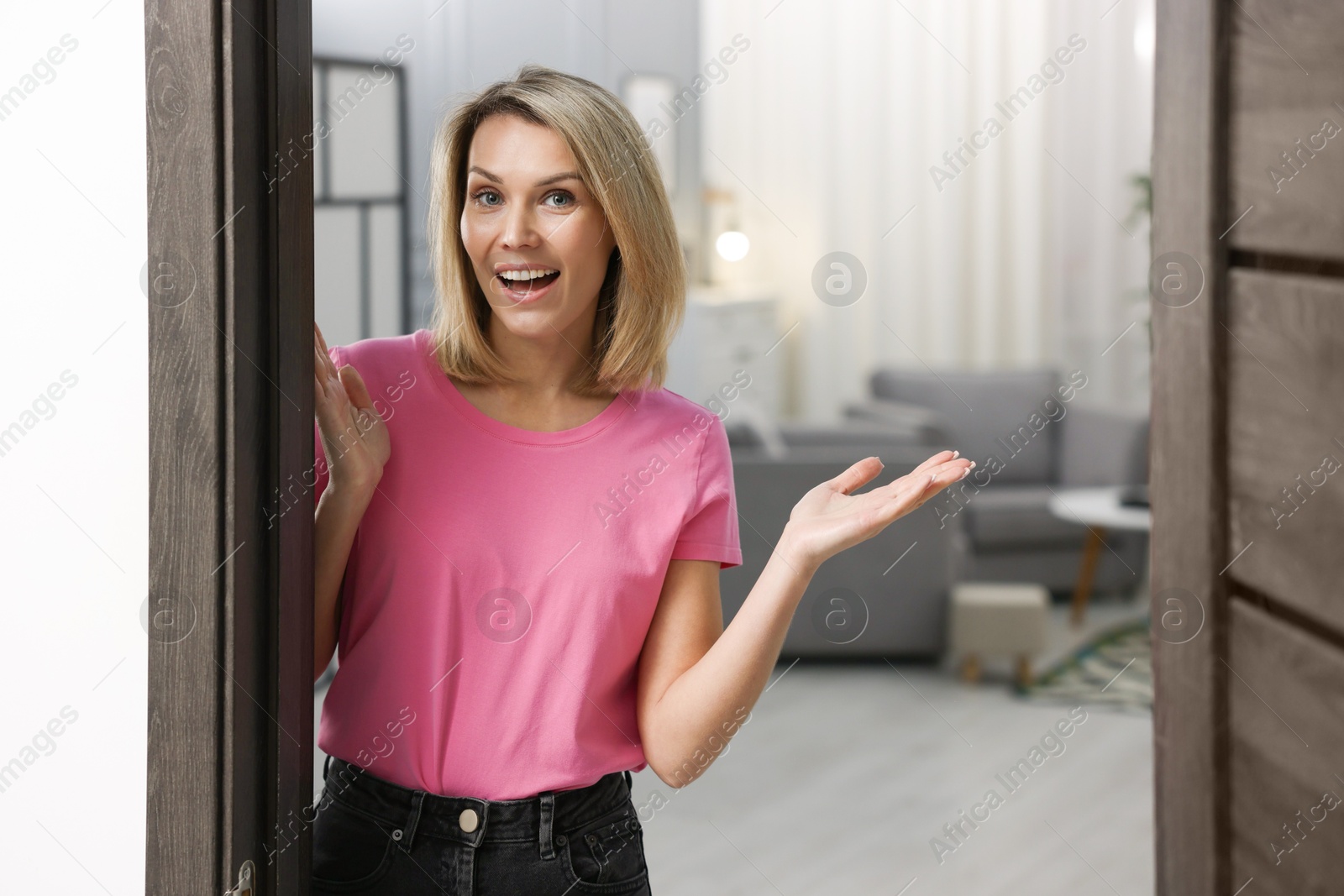 Photo of Happy woman welcoming guests to her house