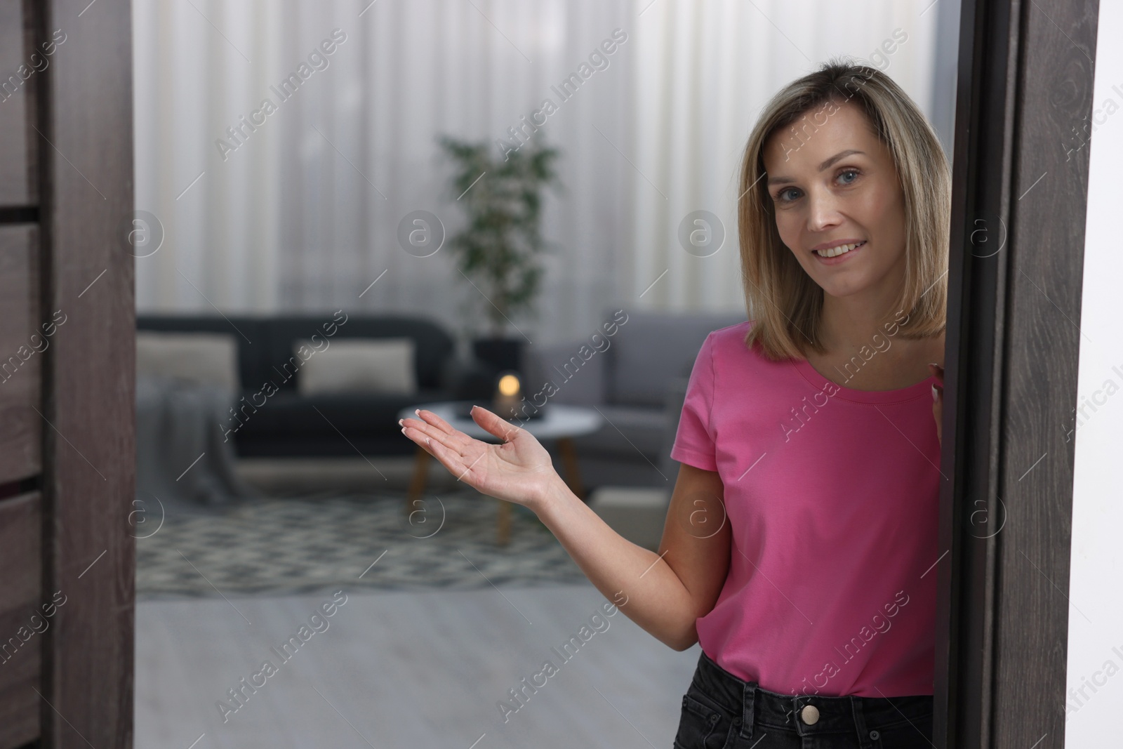 Photo of Happy woman welcoming guests to her house