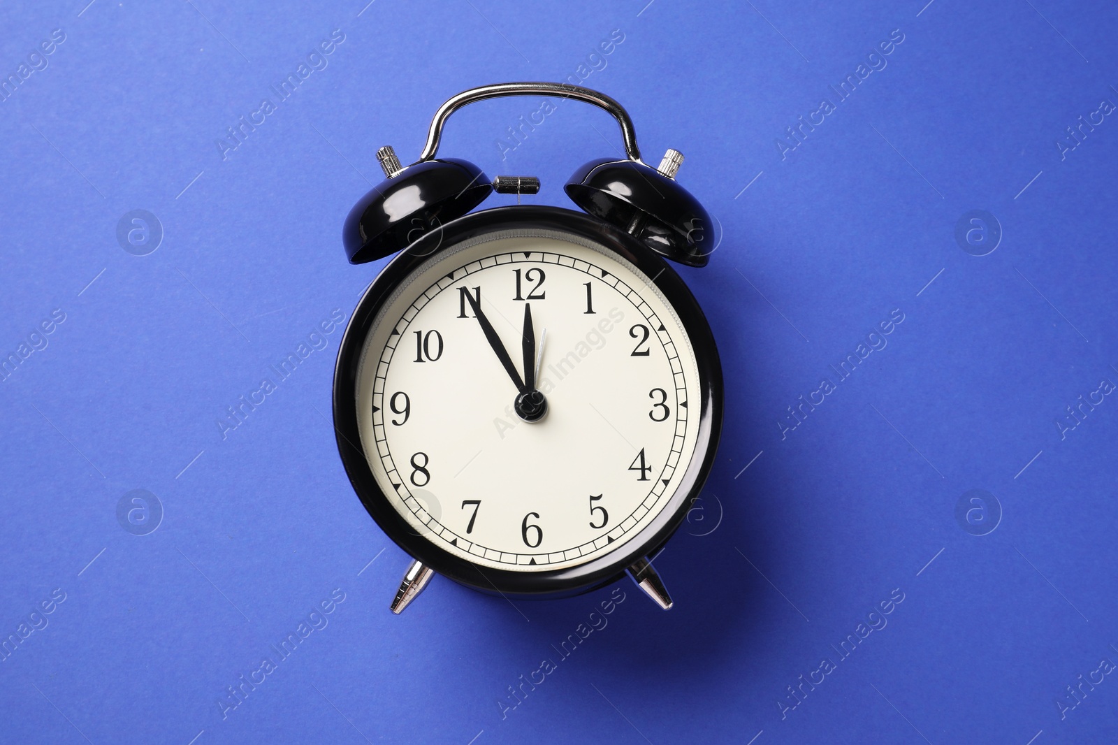 One black alarm clock on blue background, top view Photo of One black alarm clock on blue background, top view