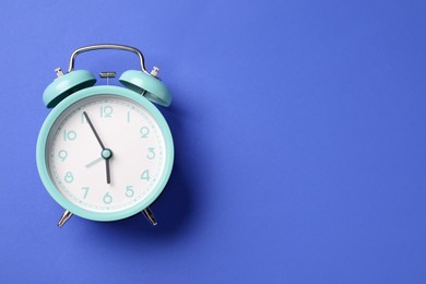 Photo of One turquoise alarm clock on blue background, top view. Space for text