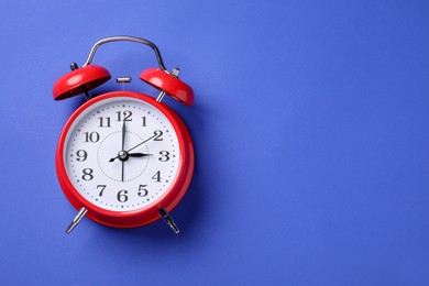 Photo of One red alarm clock on blue background, top view. Space for text