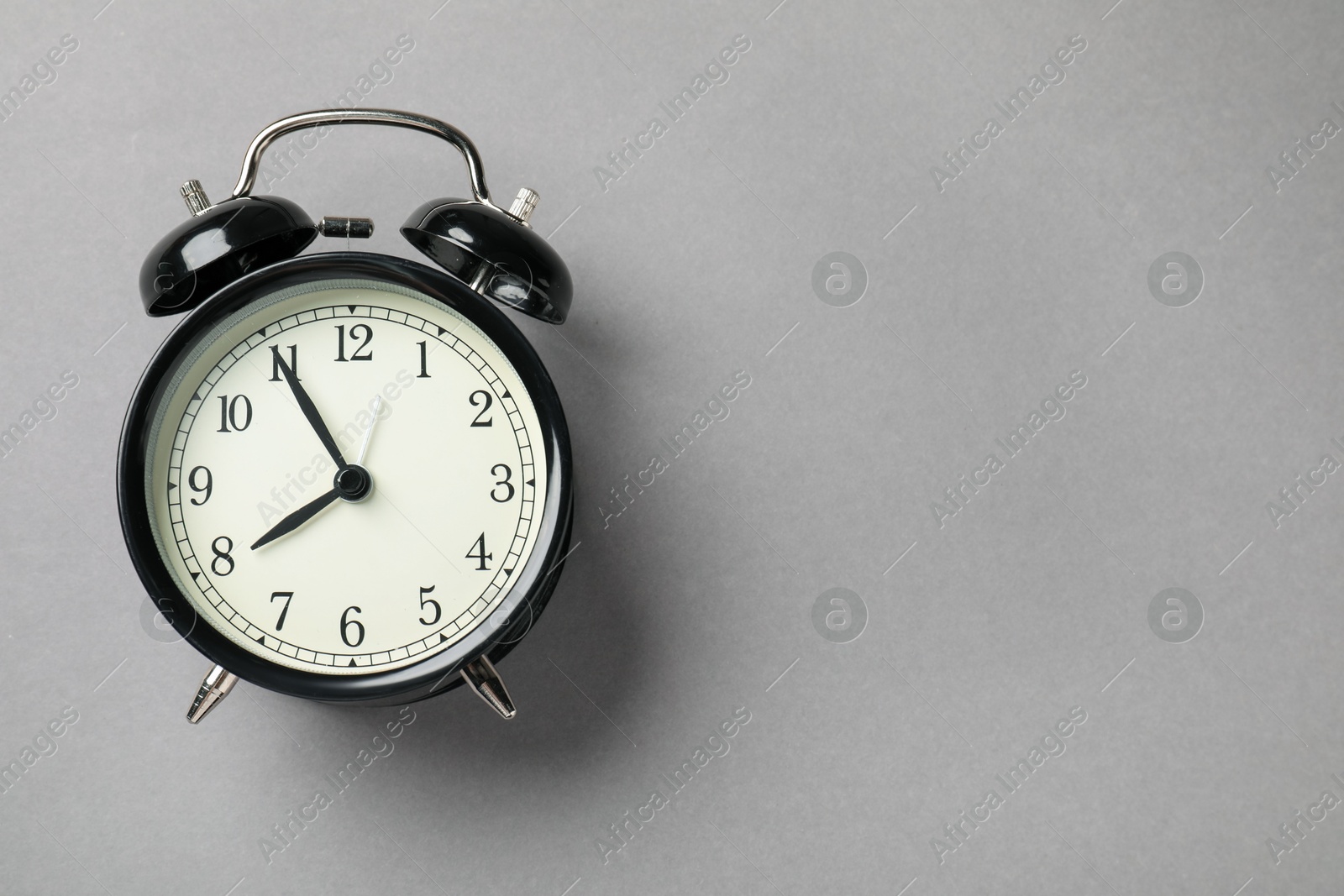 One black alarm clock on light grey background, top view. Space for text Photo of One black alarm clock on light grey background, top view. Space for text