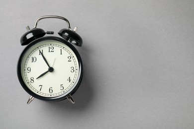 Photo of One black alarm clock on light grey background, top view. Space for text