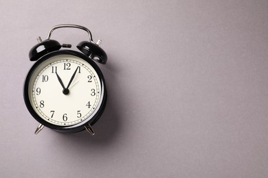 Photo of One black alarm clock on light grey background, top view. Space for text