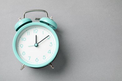 Photo of One turquoise alarm clock on light grey background, top view. Space for text