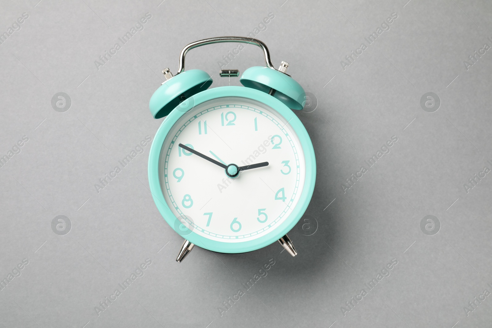 Photo of One turquoise alarm clock on light grey background, top view