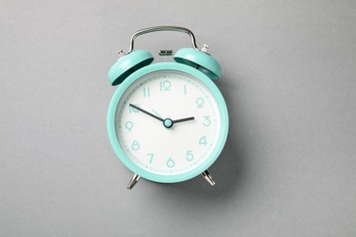 Photo of One turquoise alarm clock on light grey background, top view