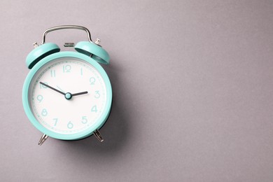 Photo of One turquoise alarm clock on light grey background, top view. Space for text